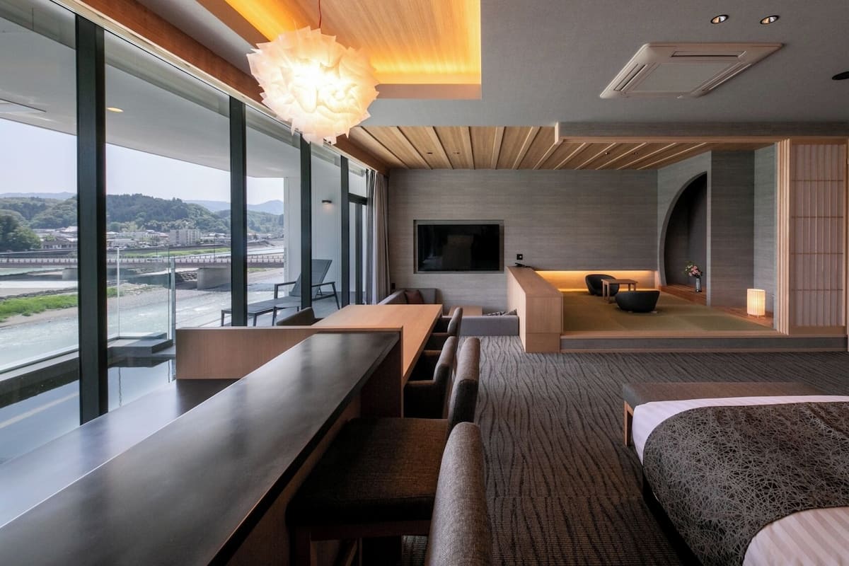 Une chambre d’hôtel moderne dotée d’une grande fenêtre, d’un canapé, d’un lit et d’une télévision.