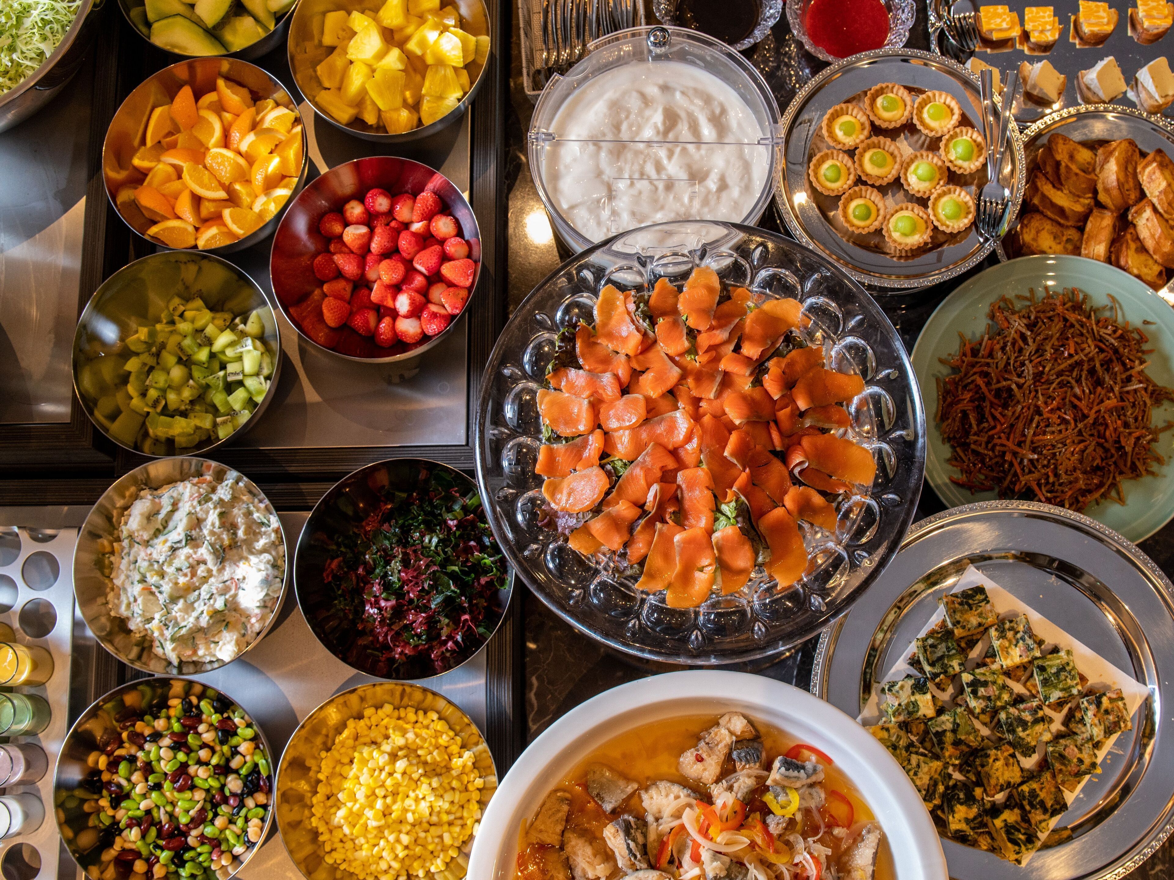A buffet with various dishes including fruits, salads, and seafood.
