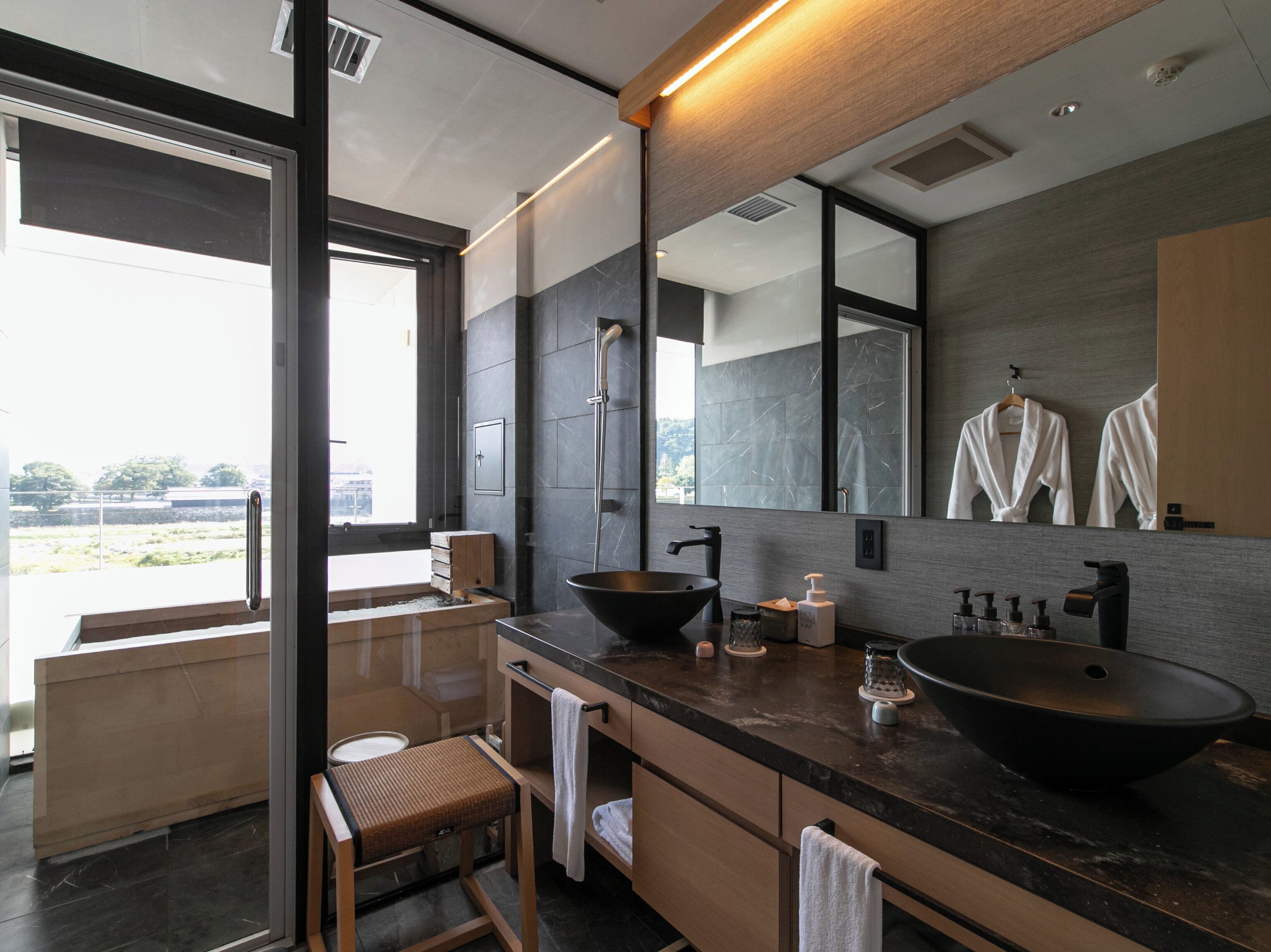 A modern bathroom with a large mirror, a black vessel sink, and a wooden vanity.