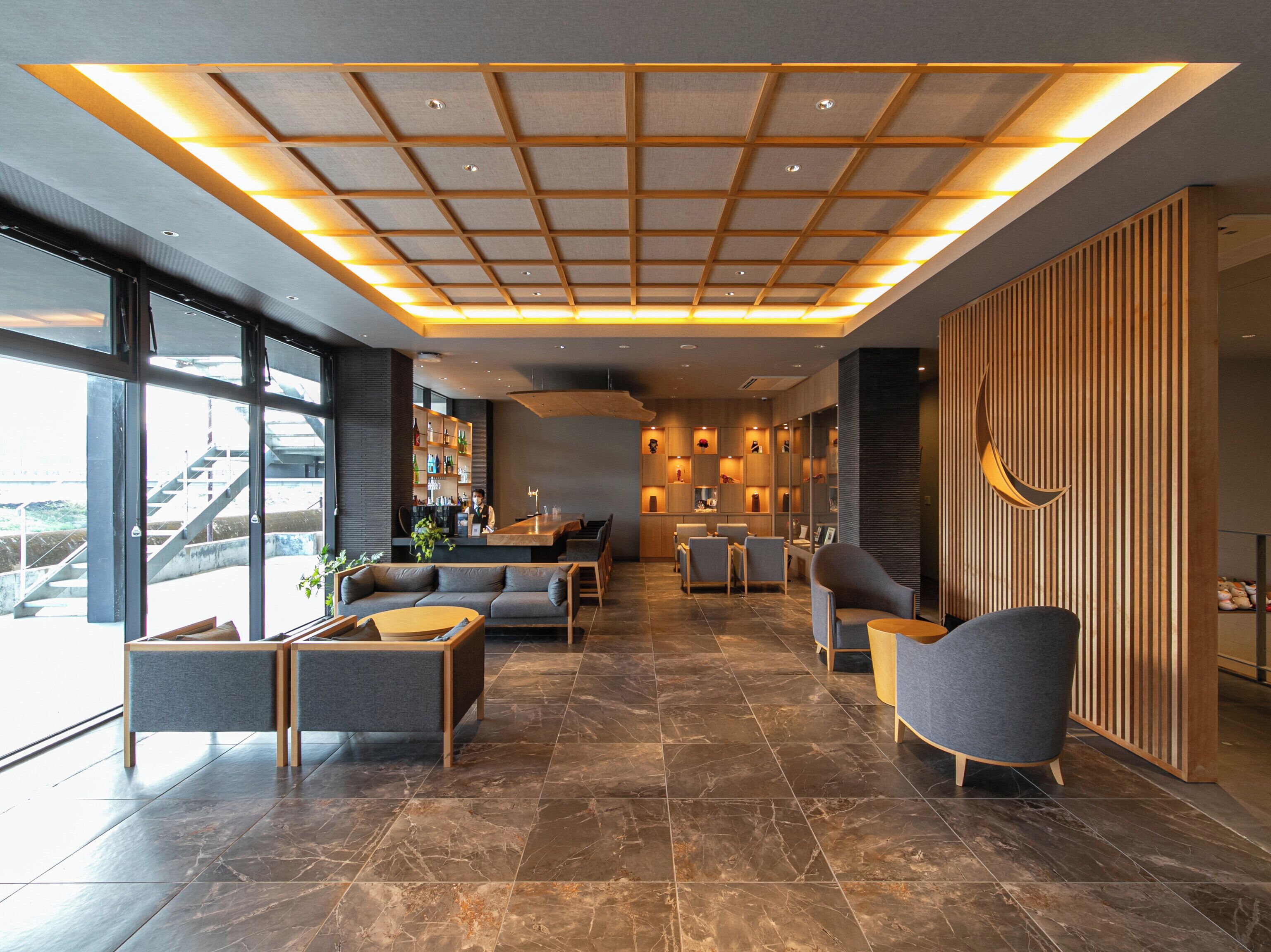 A modern lobby with a high ceiling, seating area, and a bar.