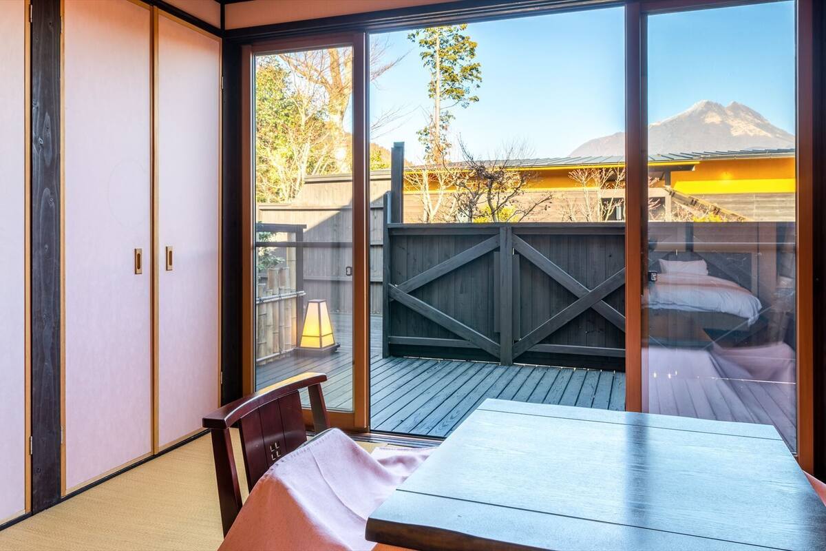 A room with a sliding glass door leading to a deck with a view of mountains.