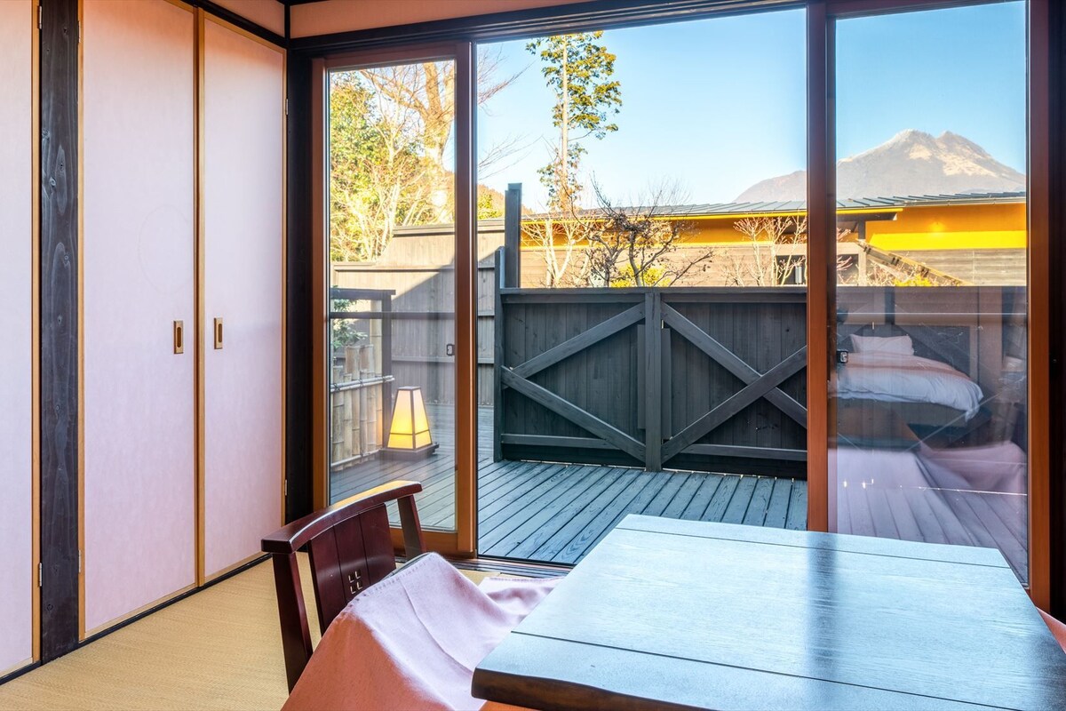 A room with a sliding glass door leading to a deck with a view of mountains.