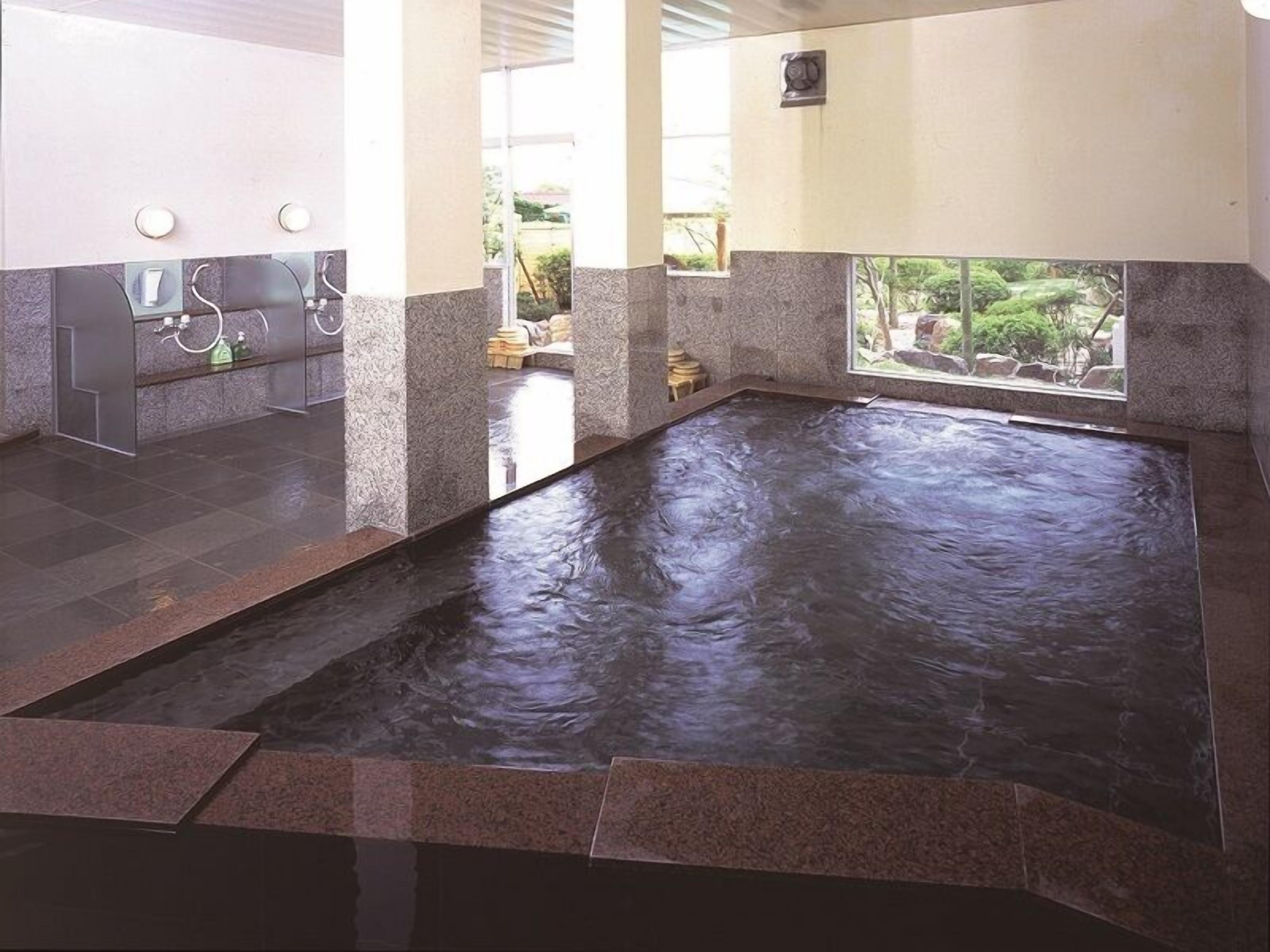 Een wellnessruimte met een bubbelbad, een receptiebalie en uitzicht op de omgeving.