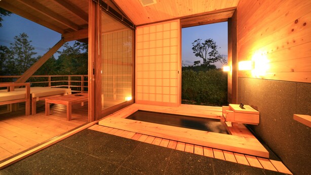 Un spa de madera con bañera de hidromasaje, puertas correderas y una zona de estar.