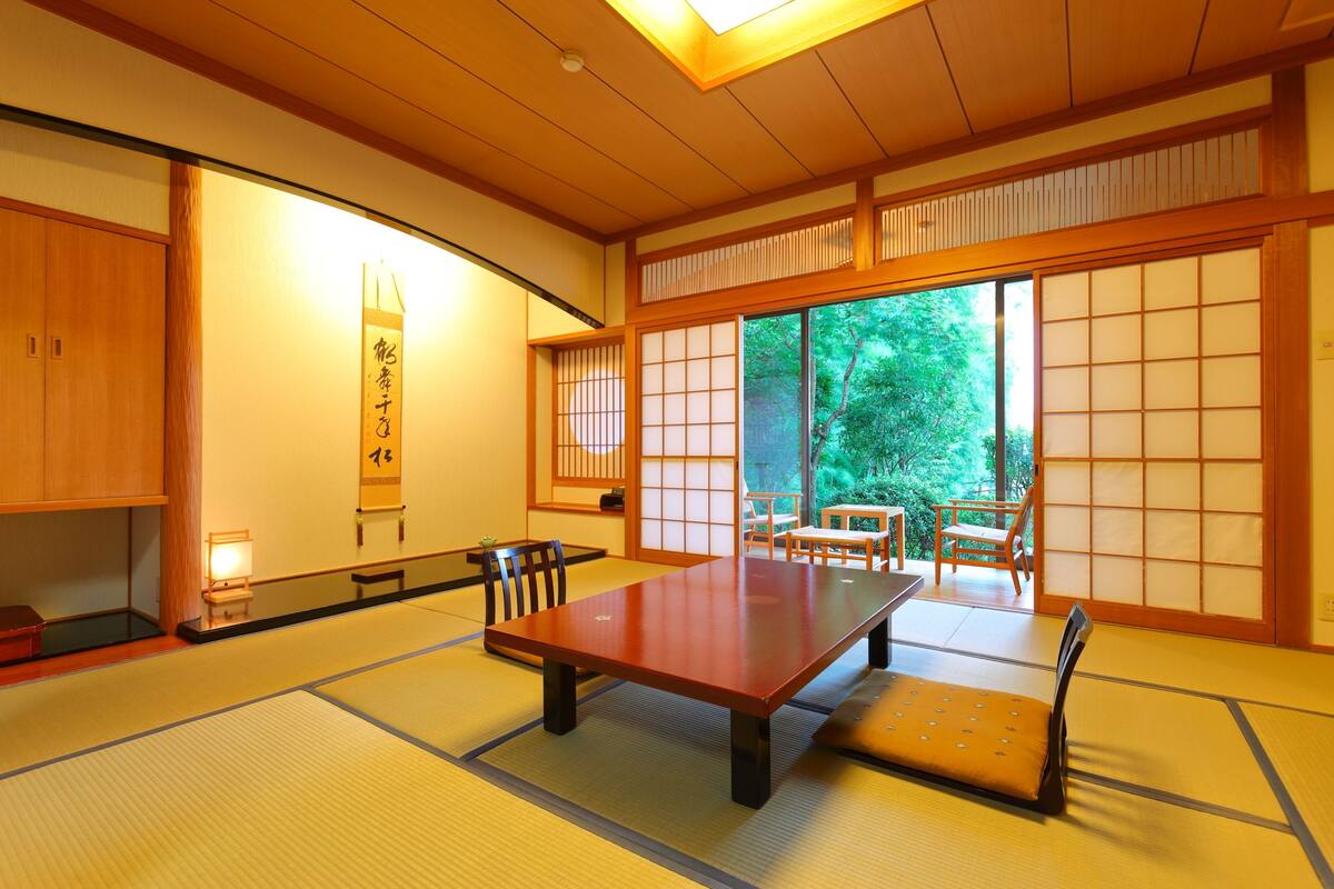 Ett traditionellt japanskt rum med tatamimattor på golvet, ett lågt bord och skjutdörrar.