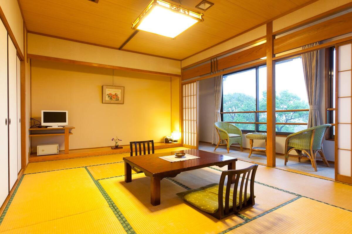 Ett traditionellt japanskt rum med tatamimattor på golvet, ett träbord och stolar.