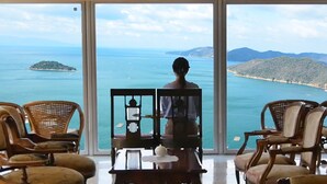 A room with a large window overlooking a coastal view, featuring a chair and a table. - Hotel Manyomisaki (Aioi)