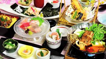 A variety of Japanese dishes including sushi, sashimi, and tempura, arranged on a tray.