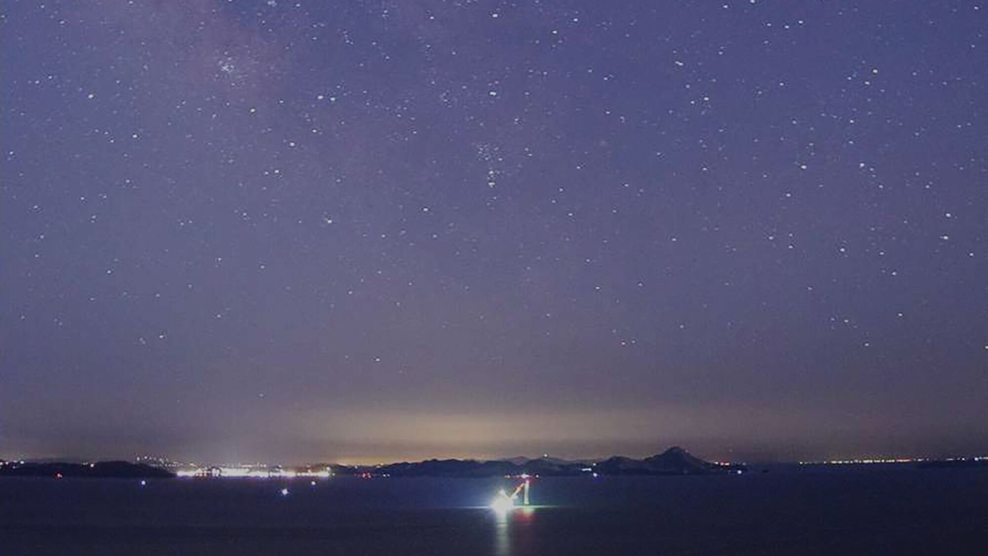 A night sky with stars and a distant mountain range.