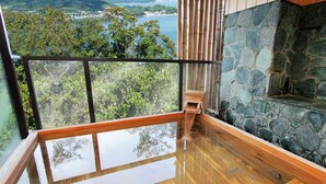 A balcony with a stone wall, wooden floor, and a view of a coastal landscape. - Hotel Manyomisaki (Aioi)