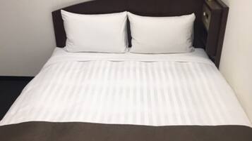 A neatly made bed with white linens and a dark headboard.