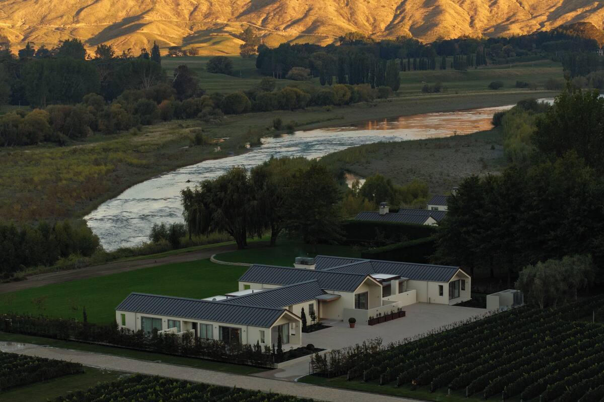 A modern building with a flat roof, surrounded by a well-maintained lawn and a river.