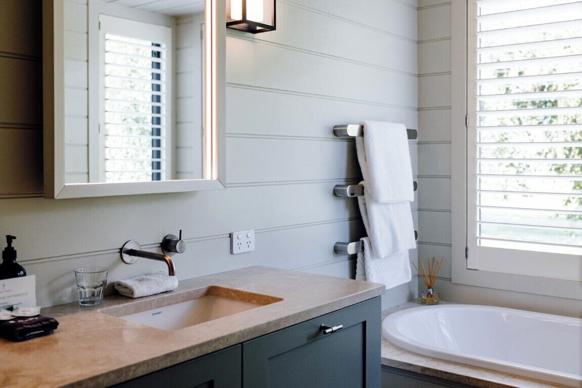 A bathroom with a sink, mirror, towel rack, and a bathtub.