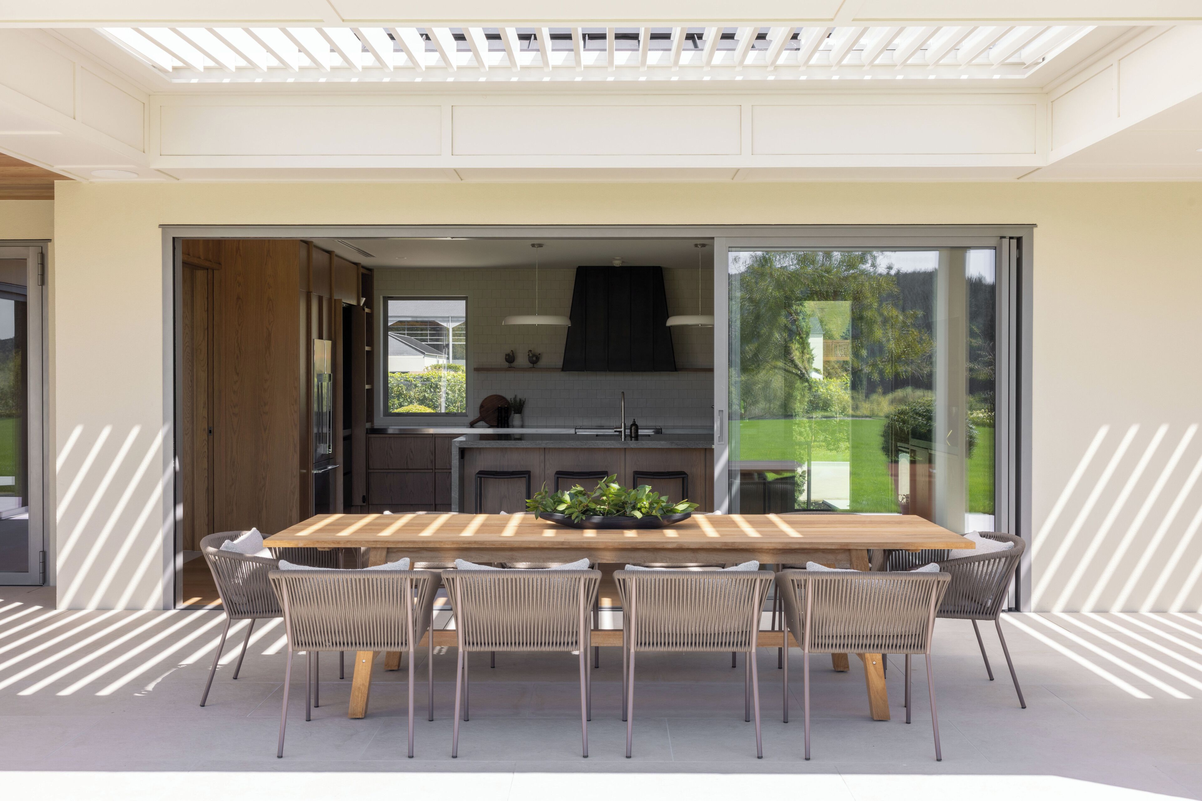 A modern kitchen with a large island, sliding glass doors to a patio, and a dining area with a wooden table and chairs.