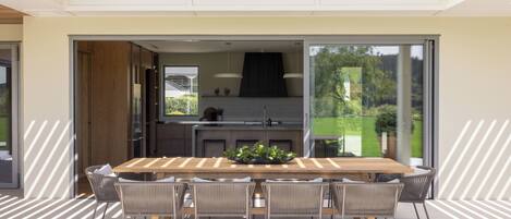 A modern kitchen with a large island, sliding glass doors to a patio, and a dining area with a wooden table and chairs.