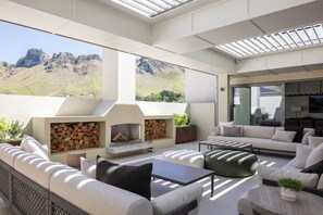 An outdoor living area with a fireplace, seating, and a view of mountains.