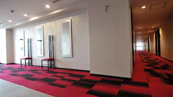 A hotel corridor with a red carpet, mirrored walls, and a number '7' sign.