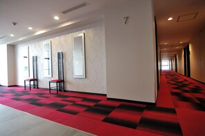 A hotel corridor with a red carpet, mirrored walls, and a number '7' sign. - Green Rich Hotel Kurume (Kurume)