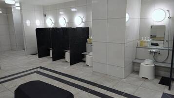 Um banheiro moderno com cabines individuais, área de pia e um espelho grande.