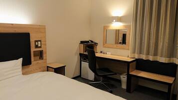 Une chambre d’hôtel avec un lit, un bureau, une chaise, un miroir et un rideau.