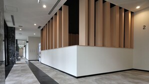 A modern hotel lobby with a reception desk, a black and white patterned floor, and a number '2' on the wall. - Green Rich Hotel Kurume (Kurume)