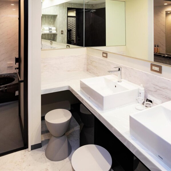 Une salle de bain moderne avec un grand miroir, deux lavabos, des toilettes et un bidet.