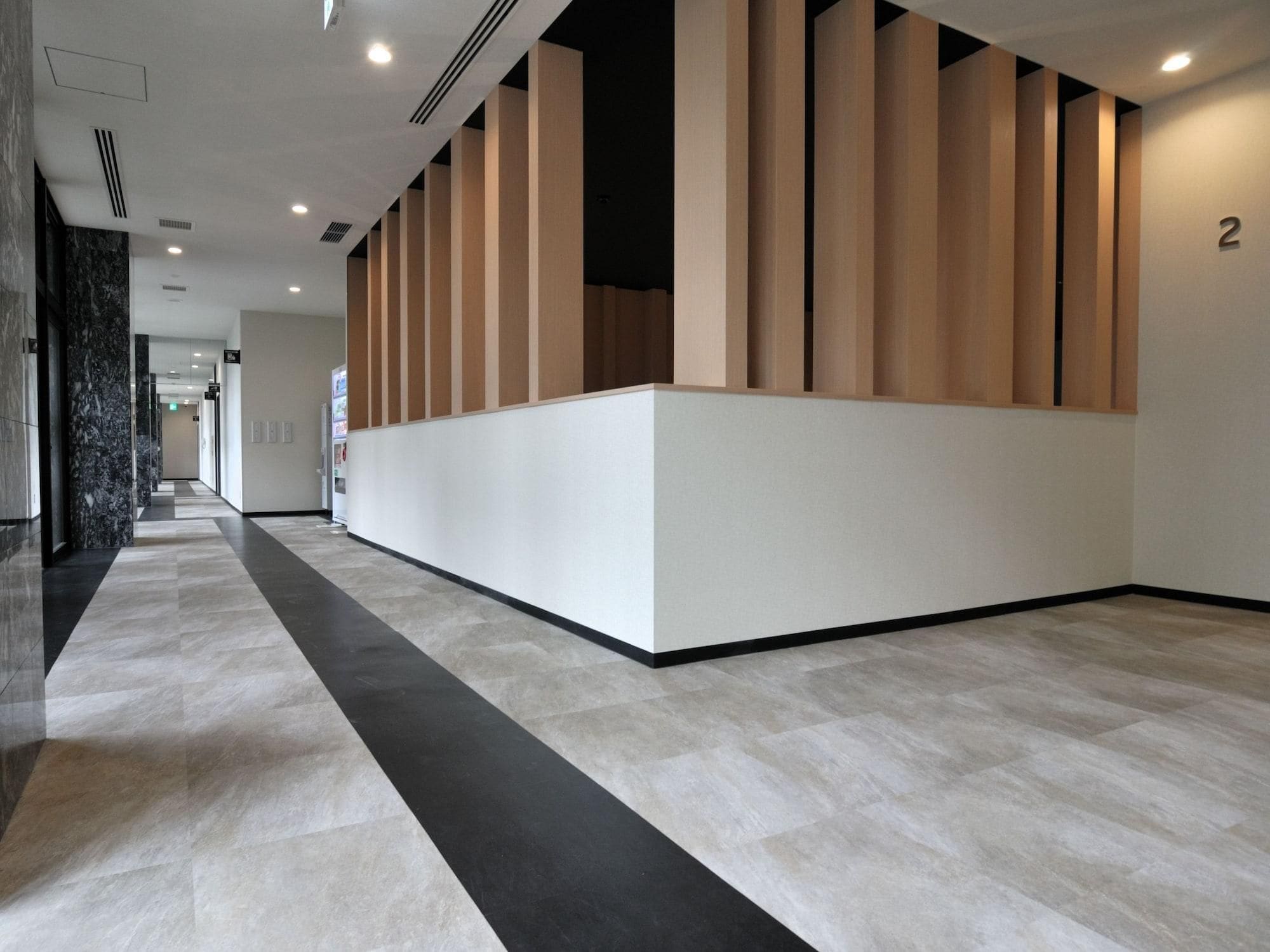 A modern hotel lobby with a reception desk, a black and white patterned floor, and a number '2' on the wall.