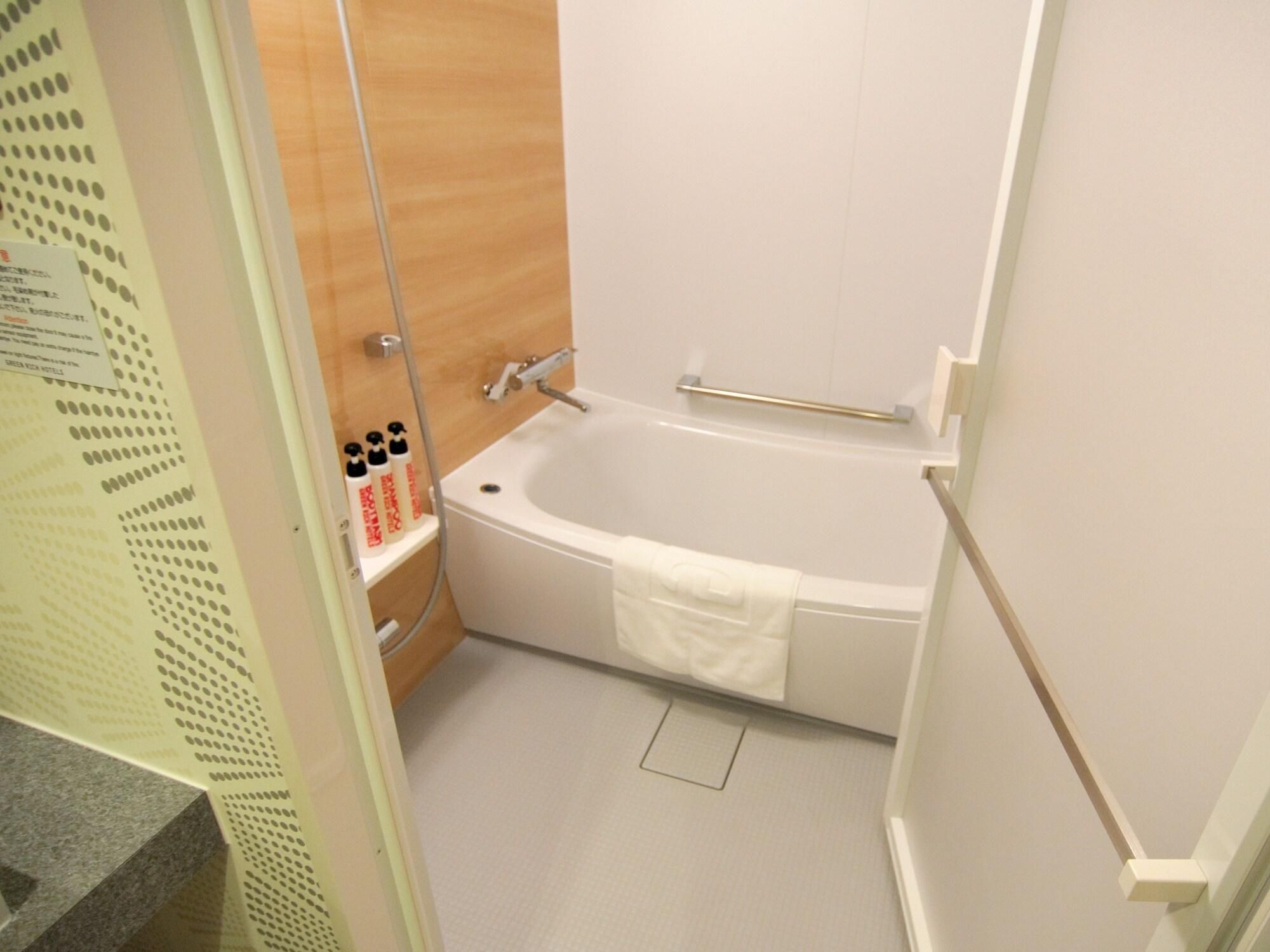Une salle de bain équipée d’une baignoire, d’une douche et d’une étagère où sont rangés les produits de toilette.