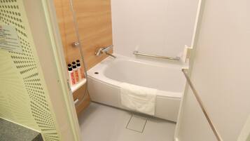 Une salle de bain équipée d’une baignoire, d’une douche et d’une étagère où sont rangés les produits de toilette.