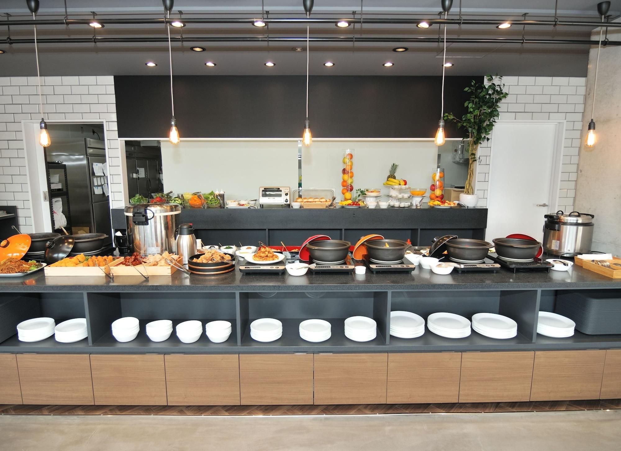 A buffet setup with various dishes, a coffee machine, and a fruit display.