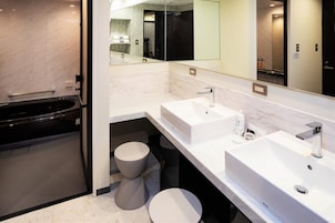 Un baño moderno con un espejo grande, dos lavamanos, una bañera y un inodoro.