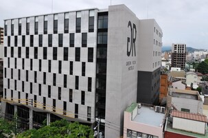Un edificio moderno con una fachada de ventanas enrejada y un llamativo letrero que dice 'Green Rich Hotels'.