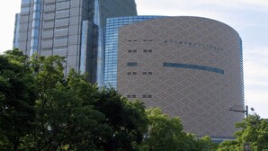 Un edifici modern amb façana corba i una estructura alta, rectangular i de vidre.