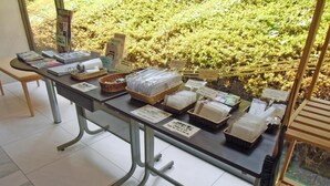 Taulell de recepció amb fulletons informatius, cistos amb objectes i vista cap a la vegetació exterior.