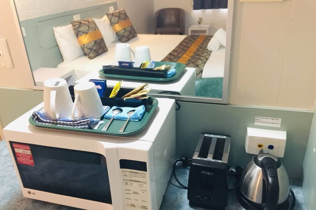 A hotel room with a microwave, a kettle, and a tray with cups and utensils.