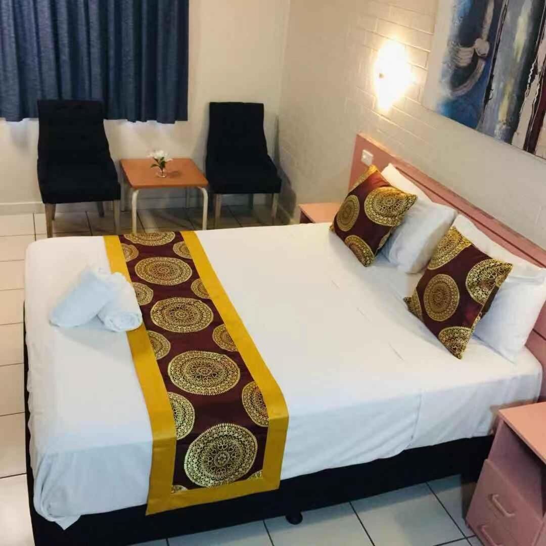 A hotel room with a bed, two chairs, a small table, and a nightstand.