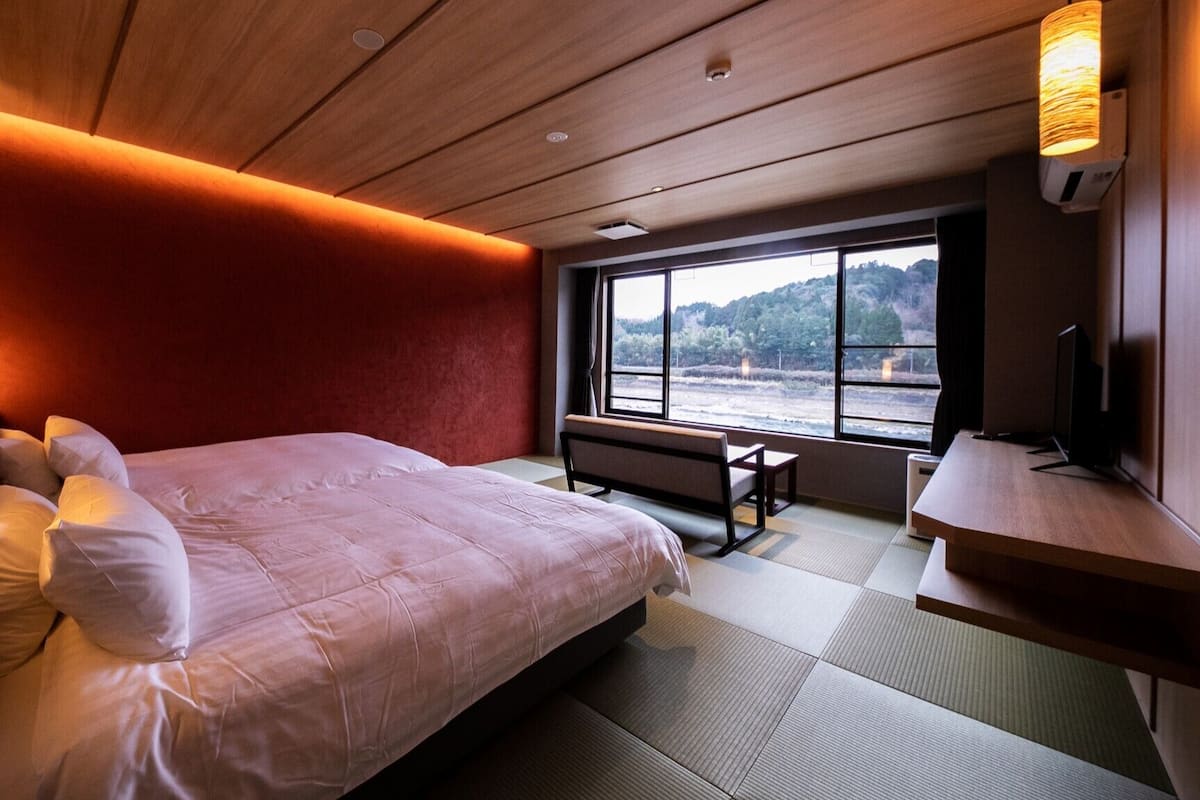 Una habitación de hotel moderna con una cama grande, un escritorio, una silla y un televisor.