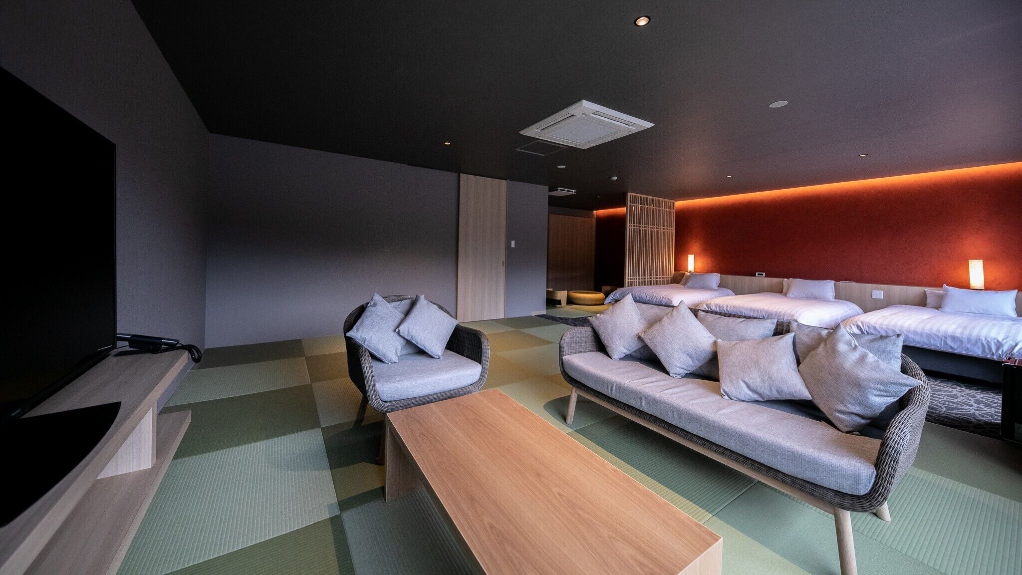 Una habitación de hotel moderna con un conjunto de sofás, una mesa de centro de madera y una televisión.