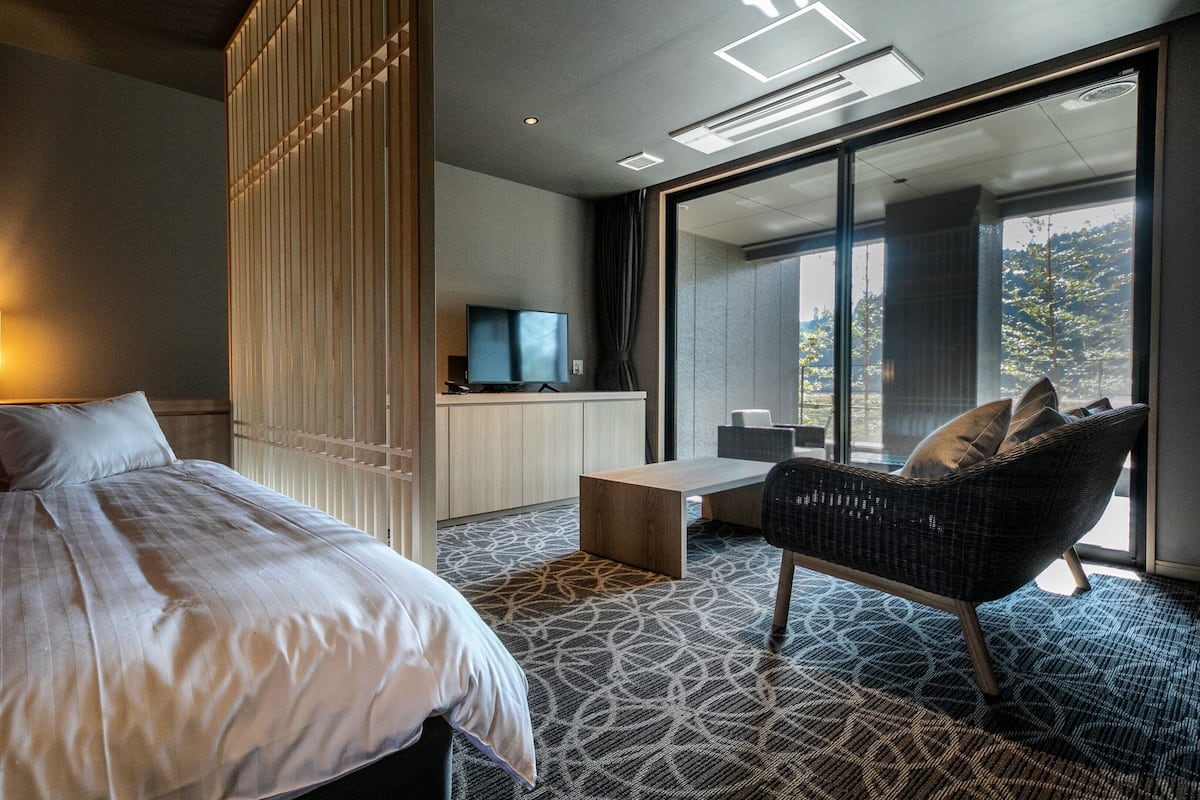 Una habitación de hotel con cama, televisión, mesa de comedor y silla.