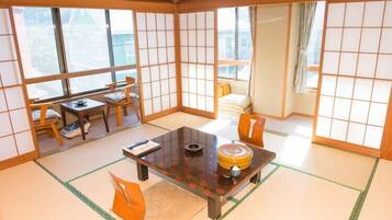 A traditional Japanese room with tatami flooring, a low table with a cushion, and sliding shoji doors.