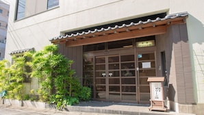 Ein Gebäude mit traditionellem japanischen Eingang, einem hölzernen Vordach und einem Schild.
