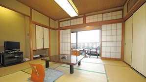 Ein traditioneller japanischer Raum mit Tatami-Bodenbelag, einem niedrigen Tisch, Stühlen und verschiebbaren Türen.