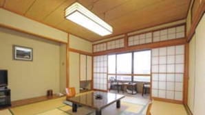 Ein traditioneller japanischer Raum mit Tatami-Boden, einem niedrigen Tisch und gleitenden Türen.