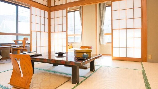 Ein traditioneller japanischer Raum mit Tatami-Bodenbelag, einem niedrigen Tisch und gleitenden Türen.