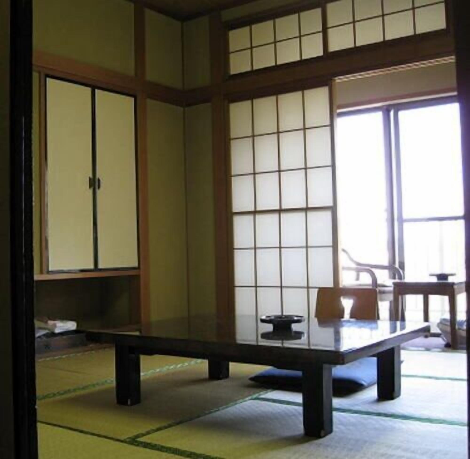 Een traditionele Japanse kamer met tatami vloerbedekking, een lage tafel en glijdende deuren.