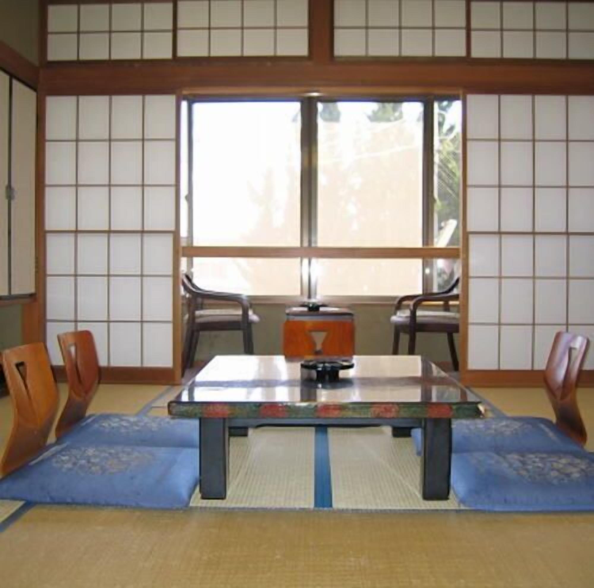Een traditionele Japanse kamer met tatami vloerbedekking, een lage tafel en schuifdeuren.
