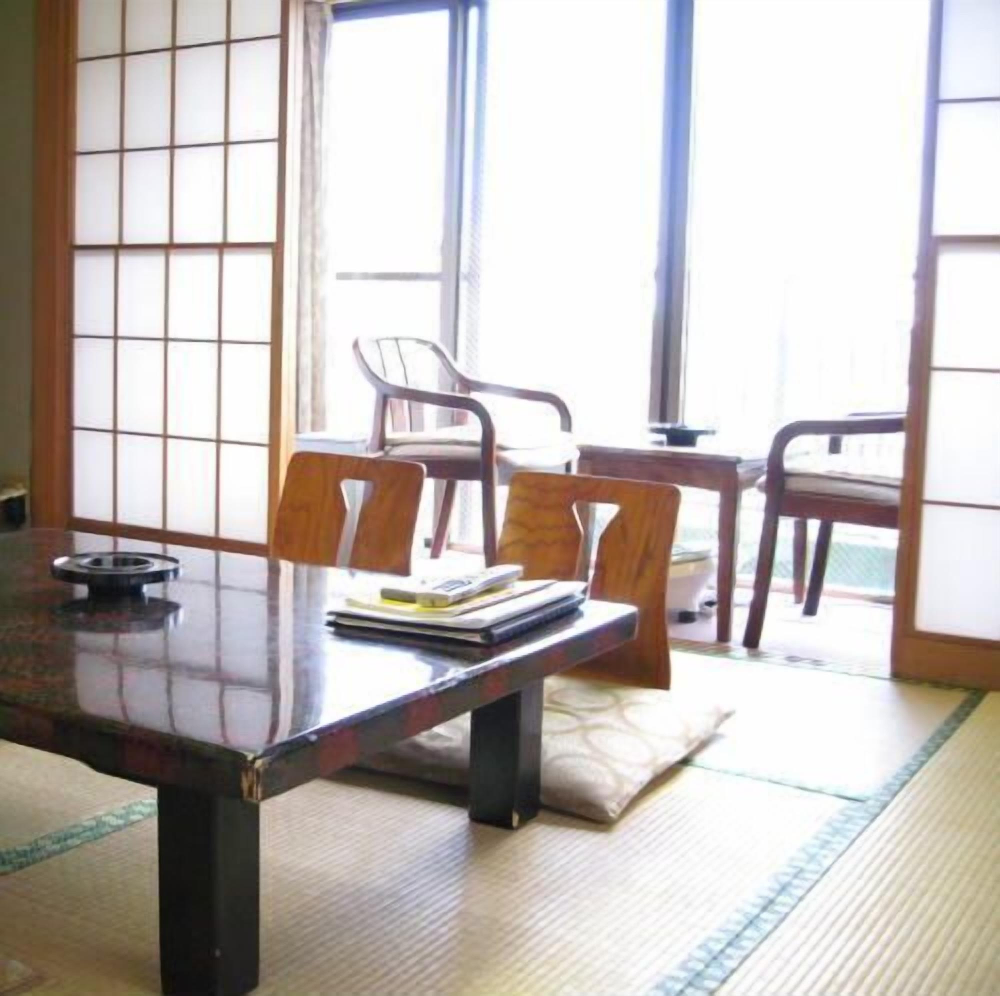 Een traditionele Japanse kamer met tatami vloeren, een lage houten tafel en twee tatami matten met stoelen.