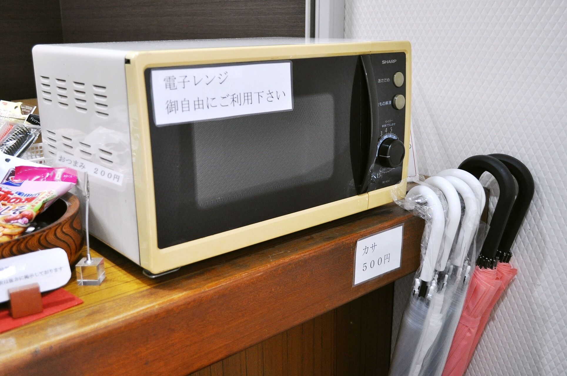 A microwave oven with a display screen and control panel, placed on a wooden counter.