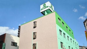 A multi-story building with a green and beige facade, featuring a prominent green sign with white text at the top. - Futsukaichi Green Hotel (Chikushino)