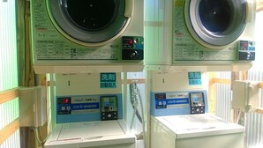 Two stacked washing machines with control panels, a water heater, and a sign indicating a 5kg capacity. - Futsukaichi Green Hotel (Chikushino)